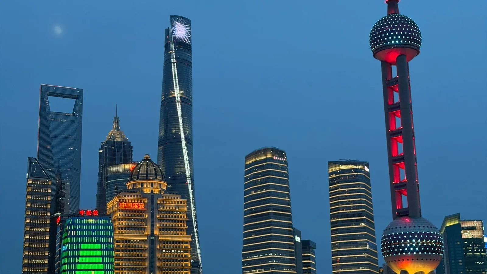 Les tours illuminées de Lujiazui et la tour de la Perle de l’Orient à Shanghai, au crépuscule.